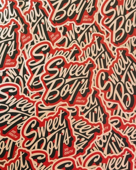 A collage of red, cream, and black Sweet Boy's logo stickers.